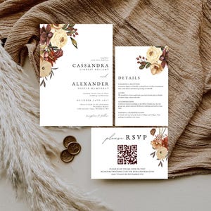 Peut inclure: Ensemble de faire-part de mariage avec des motifs floraux bordeaux, crème et verts. L'ensemble comprend une invitation, une carte de détails et une carte RSVP. L'invitation présente les noms de Cassandra et Alexander, et la date du mariage.