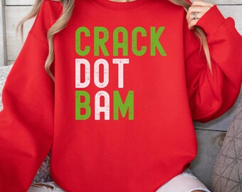 May include: A red sweatshirt with the words "CRACK DOT BAM" in green and white block letters. The sweatshirt is a crew neck style and appears to be made of a soft material.