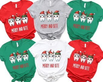 May include: Six Christmas themed t-shirts with a design of three cartoon teeth wearing Santa hats and elf hats with the text "Merry and Bite" printed on each shirt.