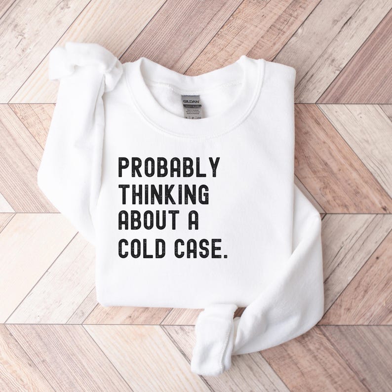 May include: White sweatshirt with black text that reads "PROBABLY THINKING ABOUT A COLD CASE."