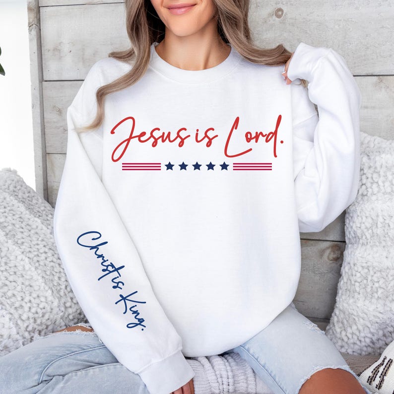 May include: White sweatshirt with the text "Jesus is Lord." in red and blue lettering. The sleeve has the text "Christ is King." in blue lettering.