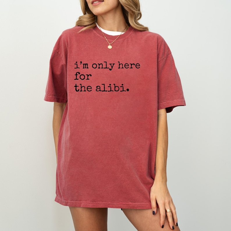 May include: An oversized red t-shirt with the text "i'm only here for the alibi." printed in black.