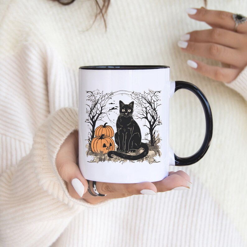 以下が含まれることがあります： 黒色の縁取りと取っ手のある白いセラミック製のマグカップ。マグカップには、不気味な森のシーンの中で、ジャック・オー・ランタンの顔をしたオレンジ色のカボチャ2つと並んで座っている黒い猫が描かれています。