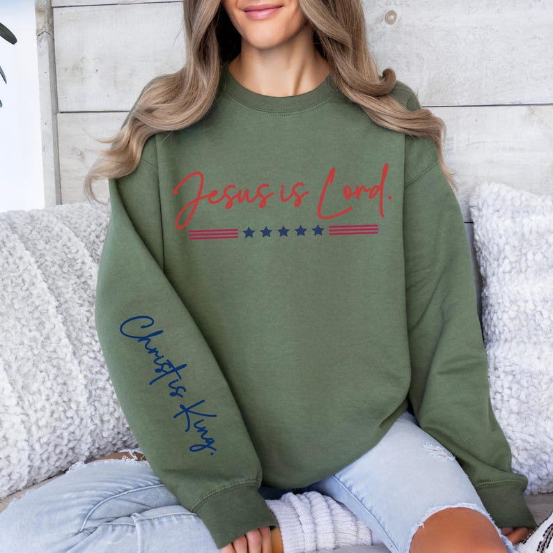 May include: A green sweatshirt with the text "Jesus is Lord" in red and white with stars and stripes. The left sleeve has the text "Christ is King" in blue.