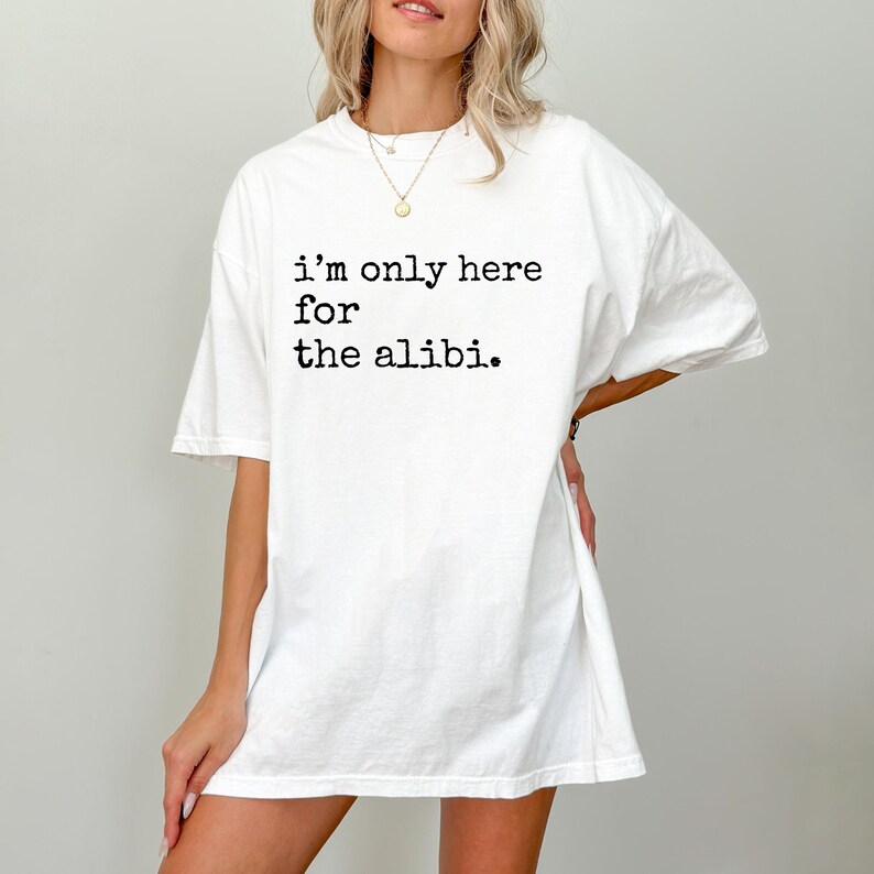 May include: White oversized t-shirt with black text that reads "i'm only here for the alibi."