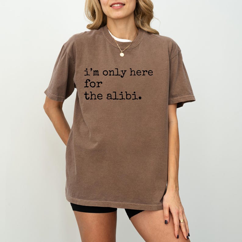 May include: A brown t-shirt with the text "i'm only here for the alibi." printed in black.