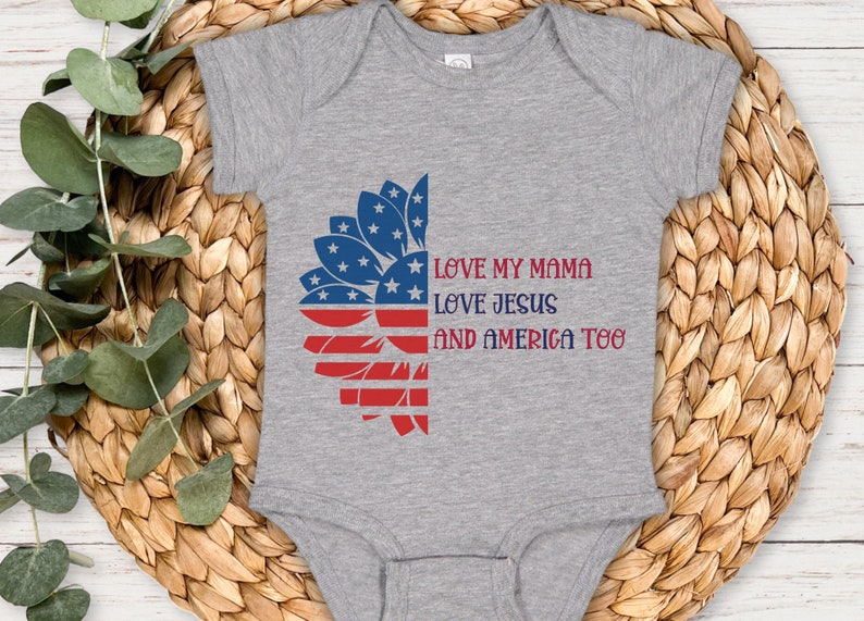 May include: A grey baby onesie with a red, white, and blue sunflower design. The onesie has the text "Love my mama, Love Jesus, and America too".