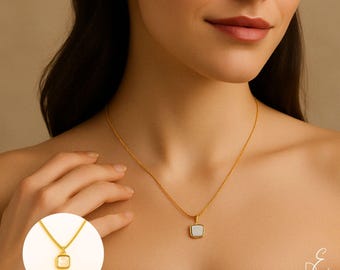 May include: A gold chain necklace with a square pendant featuring a white stone. The pendant has a gold border.