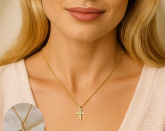 May include: A gold-colored cross pendant necklace. The cross is adorned with small, clear gemstones. The necklace is displayed on a person's neck, showcasing the delicate chain and the pendant's design. The cross pendant is a religious symbol.