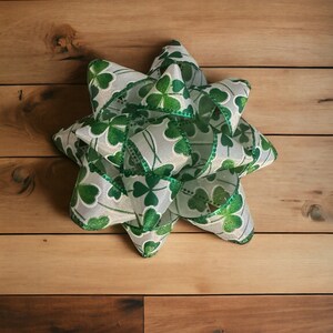 May include: A white and green bow with shamrock designs. The bow is made of a shiny, iridescent material.