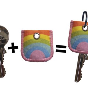 May include: A silver key with the text "WWW.KEYMAX.co.uk 109" is shown next to a rainbow-colored key cover with a pink center. The key cover is attached to a silver key with a black ring.
