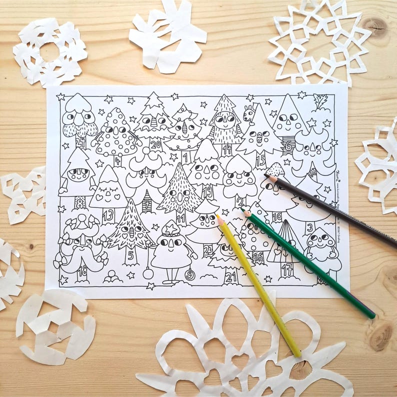 May include: A black and white Christmas-themed colouring page featuring cartoon Christmas trees with numbers. Several white paper snowflakes and three coloured pencils are scattered around the page on a wooden surface.