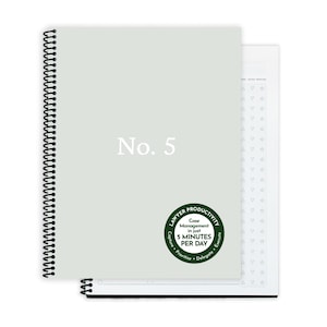 以下が含まれることがあります： 白で「No. 5」の文字が入った、ライトグレーのリング綴じノート。緑と白の丸いステッカーには「弁護士の生産性、1日わずか5分でケース管理」と書かれています。2冊目のノートが見えます。