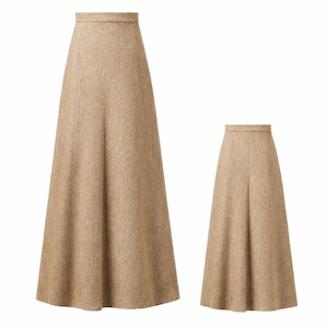 May include: Two beige, floor-length skirts. The skirts have a high waist and a flared silhouette. The fabric appears to be a textured wool or tweed. One skirt is full-length, and the other is a smaller version of the same design.