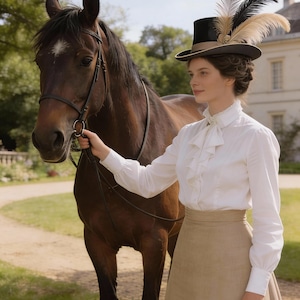 May include: A woman in a white blouse with ruffles and a tan skirt stands next to a brown horse. She wears a black top hat adorned with feathers. The scene is set outdoors with a building in the background, suggesting a historical or equestrian theme.
