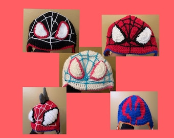 May include: Five crocheted hats featuring different Spider-Man characters. The hats are red, blue, black, white, and a combination of red, white, and blue. Each hat has a unique design with a spider web and eyes.