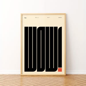 Könnte beinhalten: Gerahmtes Poster mit dem Wort "WOW!" in fetten, schwarzen, vertikalen Linien auf cremefarbenem Hintergrund. Ein kleines rotes Quadrat akzentuiert das Ausrufezeichen. Das Poster befindet sich in einem hellen Holzrahmen und wird an einer weißen Wand über einem Holzboden angezeigt.