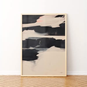 May include: Abstract art print in a light wood frame. The artwork features a composition of black, white, and pale pink brushstrokes. The lower portion is a soft beige, creating a contrast with the darker upper section. The overall style is modern and minimalist.