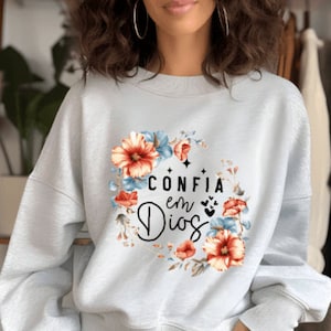 May include: A light gray sweatshirt with a floral design and the text "CONFIA en Dios" in black.