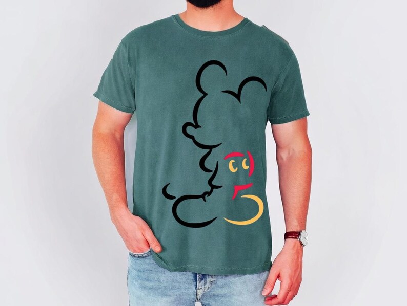 May include: Teal-colored t-shirt featuring a black outline of a cartoon mouse. The mouse has red, yellow, and black accents. The shirt is a short-sleeved crew neck.