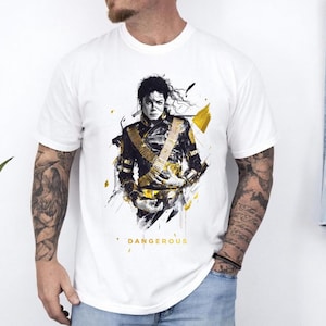 May include: A white short-sleeve t-shirt featuring a graphic illustration of a person in a black and gold military-style jacket. The design includes abstract black and yellow paint splatters and the word DANGEROUS printed in yellow text below.