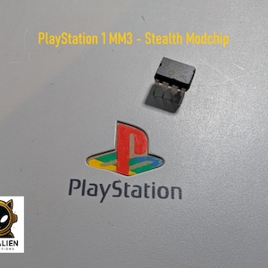 Könnte beinhalten: Graue Oberfläche mit dem PlayStation-Logo und dem Text "PlayStation 1 MM3 - Stealth Modchip". Eine kleine schwarze elektronische Komponente befindet sich über dem Logo. Das Cat Alien Productions-Logo befindet sich unten links.