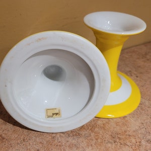 May include: Two white ceramic candle holders with yellow and white stripes. The holders are made in Japan.