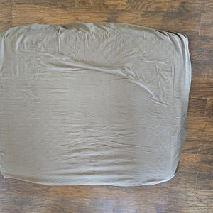 May include: A plain, light gray fitted sheet. The sheet is made of a soft, smooth fabric and is wrinkle-free.
