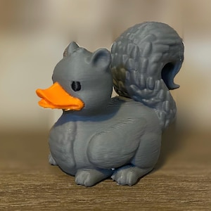 May include: A gray 3D printed duck with an orange beak and a gray bushy tail.