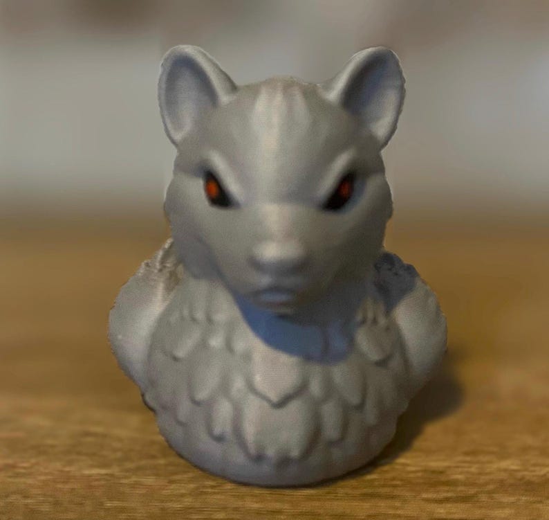 A gray 3D printed duckies shaped like wolves with red eyes. The duckies are sitting on a wooden surface. Rubber Duck style. Facing foward