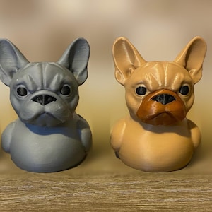 May include: Four French bulldog figurines in a row. Two are gray with black noses, and two are tan with brown noses. The figurines have detailed features and are sitting on a wooden surface.