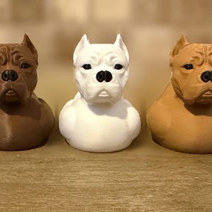Könnte beinhalten: Fünf Hundefiguren in einer Reihe, die jeweils das muskulöse Brustbild eines Hundes mit spitzen Ohren und faltigem Gesicht darstellen. Die Figuren sind in Grau, Dunkelbraun, Weiß, Hellbraun und Schwarz gehalten und haben schwarze Nasen und Augen.