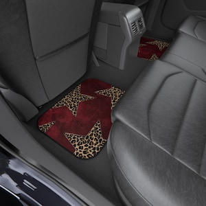 May include: Car floor mats with a burgundy background and leopard print star designs. The mats are placed in the back seat area of a car with black leather seats. The leopard print has tan and brown spots.