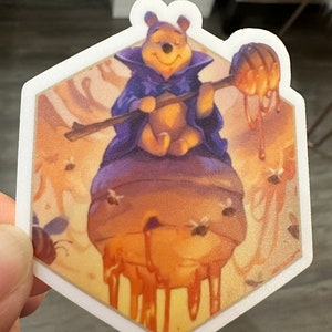 May include: Winnie the Pooh, dressed as a wizard, sits on a honey pot with a honey dipper in his hand. Bees fly around the honey pot, which is dripping with honey.