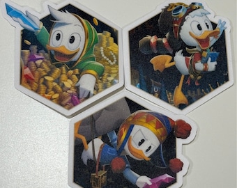 May include: Three hexagon-shaped stickers featuring Scrooge McDuck in various adventure poses. One sticker shows Scrooge in a green hooded outfit with a sword, another with goggles and a red vest, and the last in a blue outfit.