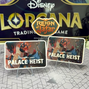 May include: Two rectangular trading card stickers with the text "PALACE HEIST" and "ILLUMINEER'S QUEST" are displayed. The stickers feature a character with red and black details. The background includes a "REIGN of Jafar" sticker and a "Disney LORCANA" box.