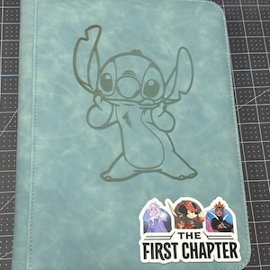 K&ouml;nnte beinhalten: Ein blaugr&uuml;ner Ordner mit einem gen&auml;hten Rand und einem hellblauen, gepr&auml;gten Bild von Stitch aus Lilo & Stitch. Der Ordner hat einen Aufkleber in der unteren rechten Ecke, auf dem "The First Chapter" steht, mit Bildern von drei Disney-Charakteren.