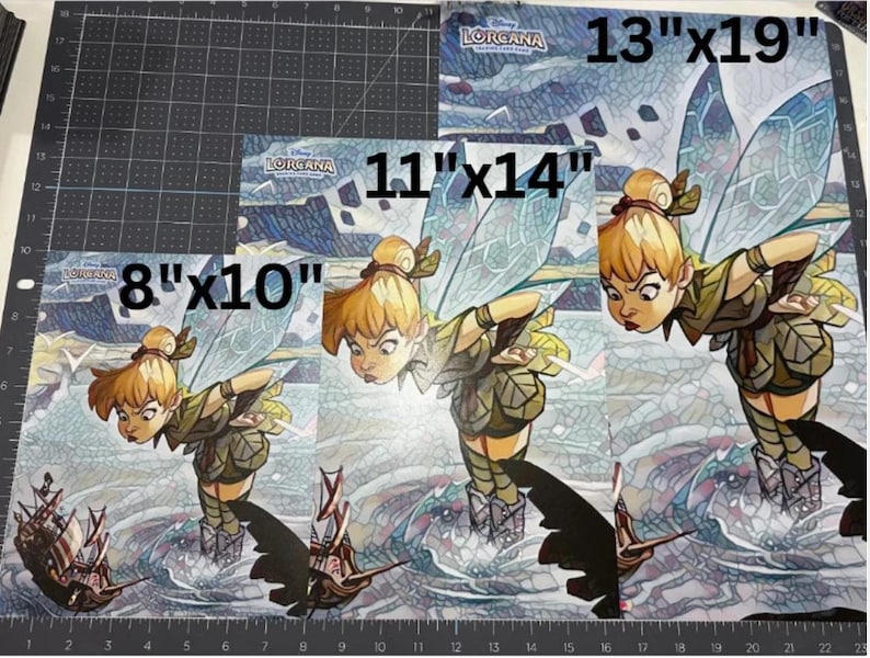 May include: Three rectangular prints featuring a Disney Lorcana illustration of Tinker Bell with wings, wearing a green outfit, hovering over a small ship. The prints are labeled with sizes 8"x10", 11"x14", and 13"x19" in black text.