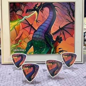 Puede incluir: Obra de arte enmarcada con un dragón que escupe fuego verde, con un diseño de dragón a juego en cuatro tarjetas triangulares. La obra está en un marco blanco, con la palabra "Lorcana" visible. Las tarjetas están etiquetadas como "Champion".