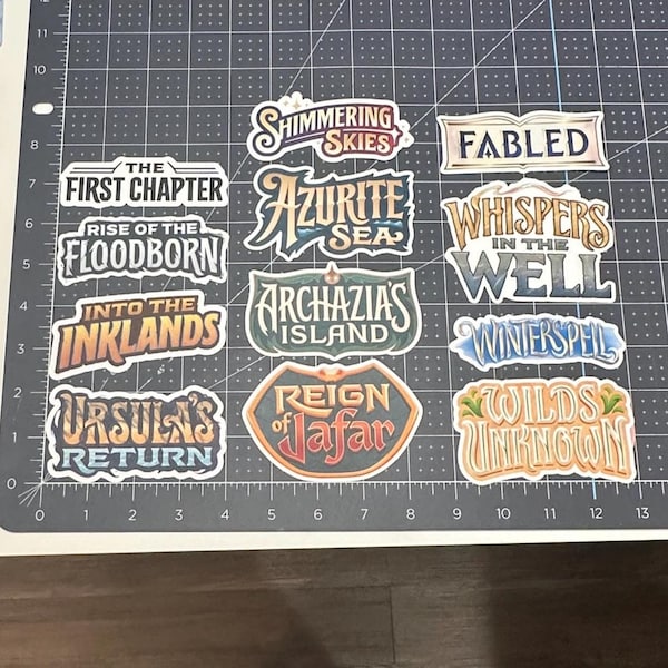 Etichette Lorcana - Adesivi - Decalcomanie / Tutti i set - Il primo capitolo di Wilds Unknown / Raccoglitori, scatole per mazzi di carte, organizzazione dei set