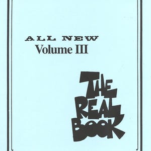 Pode incluir: Uma capa de livro azul claro com uma borda decorativa preta. O texto "ALL NEW Volume III" está no topo, e "THE REAL BOOK" está em uma fonte estilizada na parte inferior. A capa tem uma estética vintage.