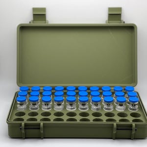 May include: A green plastic case with a hinged lid, containing 36 clear glass vials with blue caps. The vials are arranged in a grid pattern within the case.