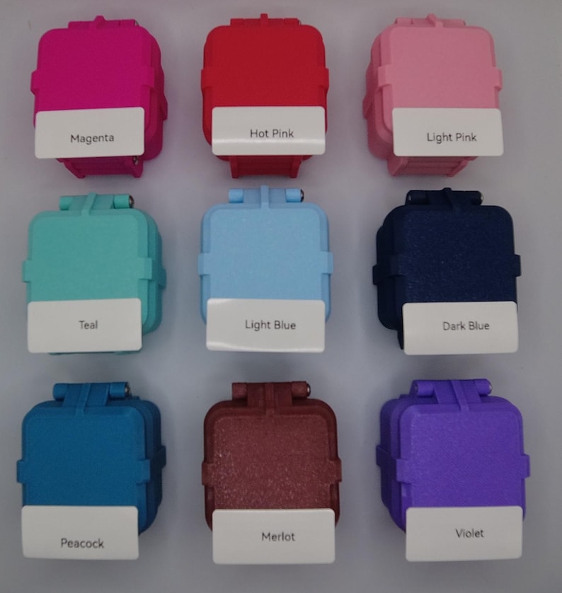 May include: Nine small square containers with different colors, including magenta, hot pink, light pink, teal, light blue, dark blue, peacock, merlot, and violet. Each container has a label with the color name.