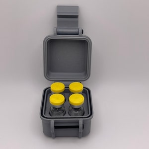 May include: A gray plastic case with a hinged lid, containing four small glass vials with yellow caps. The case has a carrying handle.