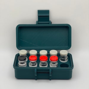 May include: A dark green, hard-sided case with a latch, containing eight small glass vials with red and white tops. The vials are arranged in two rows of four.