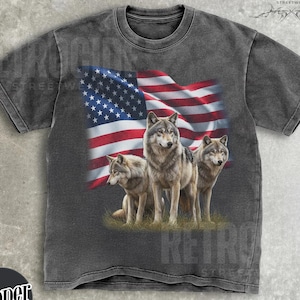 May include: Dark gray t-shirt featuring a graphic of three wolves in front of a waving American flag. The shirt has a distressed look and the word "Pepper" is printed on a black circle.