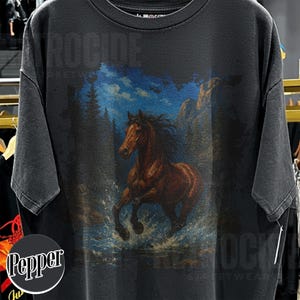 May include: Dark grey t-shirt with a brown horse graphic running through water, with a blue sky and trees in the background. The shirt has the text "ROCIDE STREETWEAR" printed at the top and bottom.