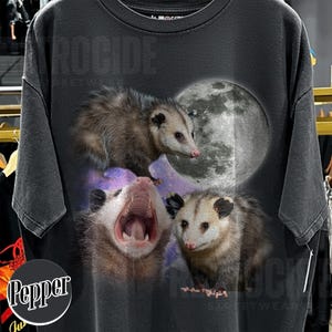May include: Dark grey t-shirt with a graphic of three opossums and a full moon. The opossums are in different poses, one yawning. The shirt has the text "ROCIDE STREETWEAR".