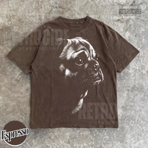 May include: A brown short-sleeve t-shirt featuring a white graphic illustration of a pug dog's face in profile. The shirt has a crew neckline and a faded, washed appearance. The text RETROCIDE STREETWEAR is visible in the top right corner.