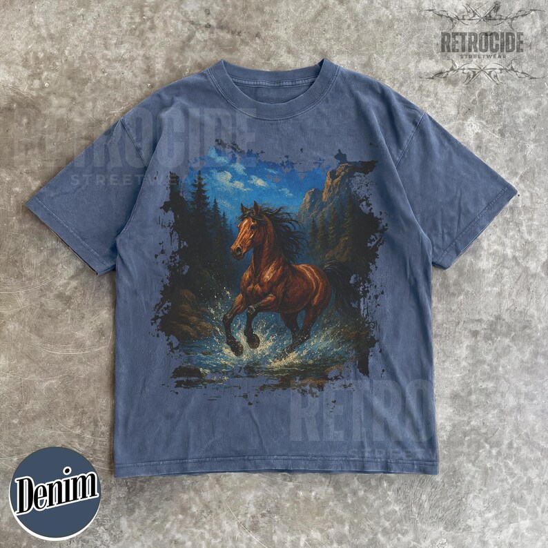 May include: Denim blue t-shirt with a brown horse graphic running through water, set against a mountain and forest backdrop. The shirt has a vintage look with the text "RETROCIDE STREETWEAR" and "Denim".